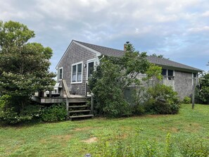 View from the driveway. Outdoor shower and clothesline to the right.