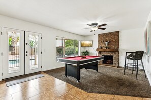 Game room just off the kitchen, featuring a pool table, smart TV, and a cozy fireplace