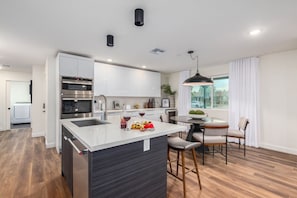 Elaborate kitchen with stainless steel appliances and a kitchen island with bar seating for 3 guests.