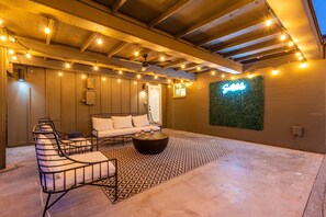 Gorgeous private backyard featuring a private pool, sun loungers, shaded patio with outdoor seating, and yard games like corn hole and giant jenga.