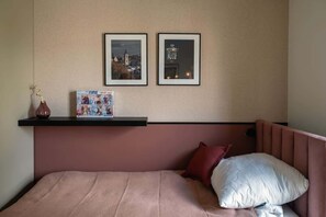 A warmly toned bedroom with a pink bedspread and cozy pillows offers a comfortable sleep and a welcoming atmosphere.