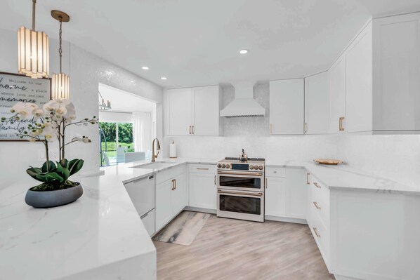 The luxurious kitchen has a  mother of pearl backsplash and quartz counter tops