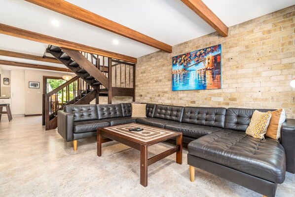 Spacious lounge room furnished with a large leather lounge and TV.