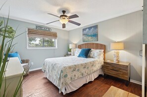 The primary suite offers a queen bed, ensuite bathroom, TV, & ceiling fan