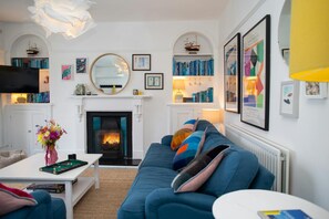 Sitting room with large blue sofa and colourful cushions. Coffee Table