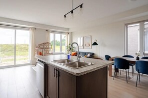 Open-concept living with natural light, a modern kitchen, and serene outdoor views.
