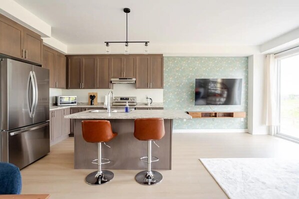 Sleek kitchen with modern appliances, stylish bar seating, and cozy open space.

