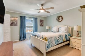 Cozy and modern retreat — unwind in this stylish bedroom featuring a sleek lampshade, smart TV for entertainment, and a ceiling fan for ultimate comfort.
