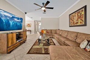 Cozy living room with a large sectional sofa, modern entertainment system, and tasteful artwork creating a warm and inviting atmosphere