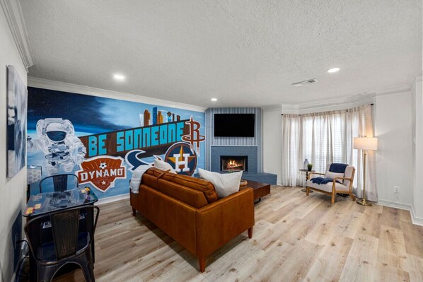 Unit 601 The spacious living room has a Houston Inspired mural, retro arcade game, pull out queen sofa, and a smart TV