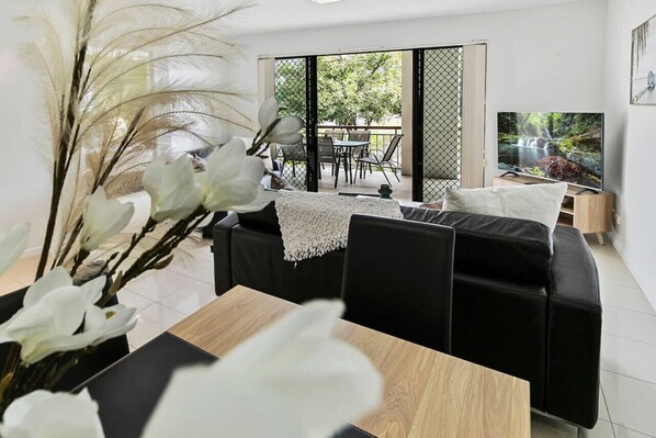 Living room with Smart TV, AC, ceiling fan and access to private balcony