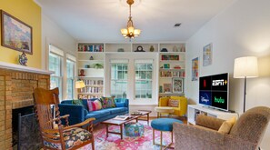 Colorful and bright living room with books, fireplace, smart tv and comfy seating!