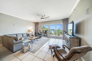 The living room offers ample, comfortable seating, a large flat screen television, 10-foot ceilings with crown molding, and breathtaking views of the Gulf of Mexico.