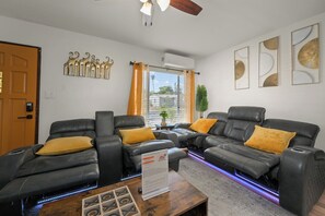 Inviting living room with black sofa, large TV, and yellow accents.
