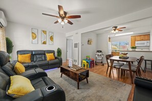 Inviting living room with black sofa, large TV, and yellow accents.