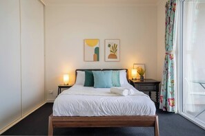 The first bedroom includes a queen-sized bed, with plenty of wardrobe space and access to the balcony.
