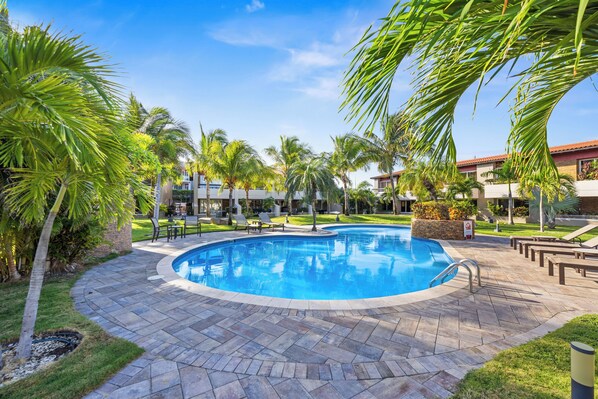 Refreshing pool with palm trees, stone decking, and a tranquil tropical setting.