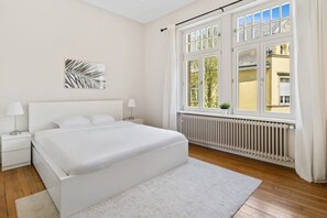 Bright and airy bedroom featuring a large window that fills the space with natural light and offers a tranquil view.