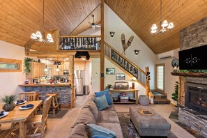 Enjoy this cozy cabin with open floor plan, stone fireplace, & loft view charm.