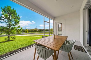 - Cozy outdoor patio with a wooden dining table, perfect for enjoying meals or relaxing in the fresh air - Screened-in for comfort, offering a beautiful view of the green lawn and landscape - Ideal for outdoor gatherings or peaceful morning coffee