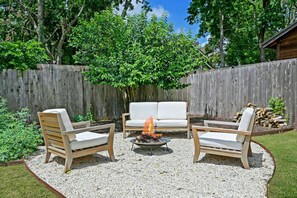 A cozy fire pit area in the backyard where you can gather with friends and family to enjoy warm conversations, roast marshmallows, and create lasting memories together.