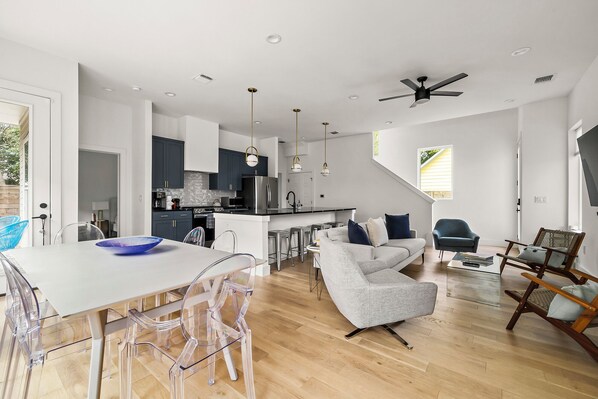 This dining area features a contemporary white square table surrounded by six transparent chairs, creating a sleek and airy look.