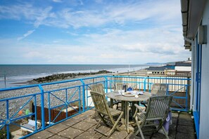 Patio area with table and chairs, view of the beach and sea