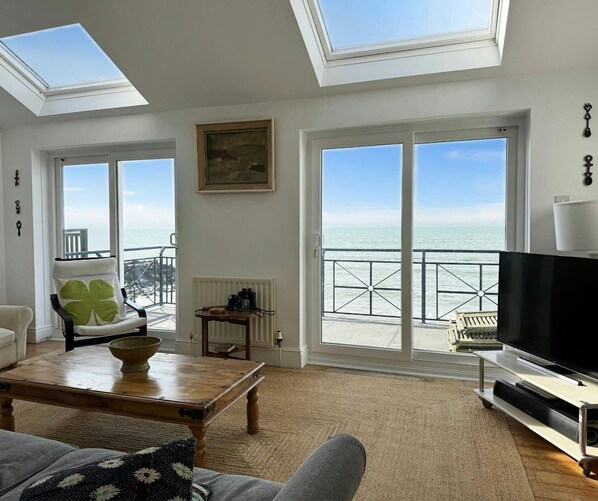 Sitting room with sofa, coffee table, tv, doors to terrace and sea view