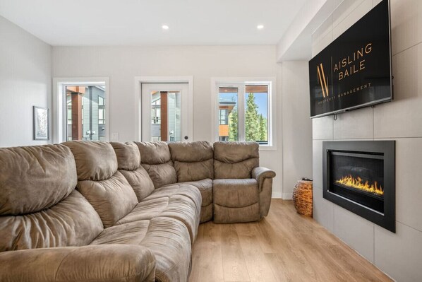 Living room on the main level with a cozy couch, gas-lit fireplace & access to the patio space.