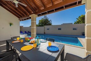 Enjoy delicious meals under the shade of this covered patio overlooking the pool.
