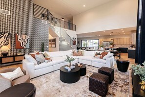Bright and open living space with vaulted ceilings connecting the entry living room, formal dining area, and kitchen. Enjoy designer furnishings and a 70"smart TV in the entry living room