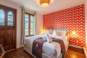 Bright and welcoming primary bedroom featuring a queen bed, vibrant wallpaper, and access to a private deck.