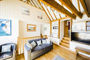 Sofa, chair, TV, ceiling beams, steps to bedroom