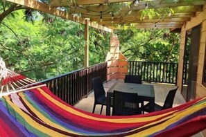 The large balcony balcony of the top Floor amongst the trees, showing hammock and outdoor shower