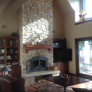 Door County Stone fireplace with large TV and 12' patio door to covered porch.