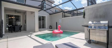 Enjoy sunny days by this private pool with a fun pink flamingo float and outdoor dining area, perfect for relaxing and entertaining!