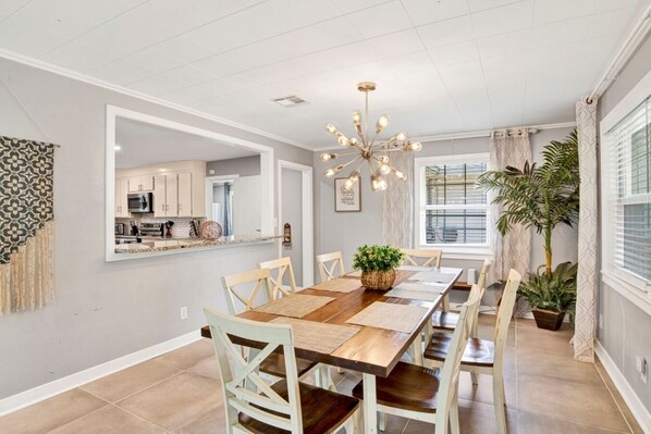 Spacious dining table for eight, seamlessly flowing into the open-concept kitchen, all beautifully lit by a modern sputnik chandelier