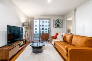 Relax in the cosy living room, featuring stylish decor and a smart TV, creating a warm, inviting atmosphere perfect for entertainment and unwinding.