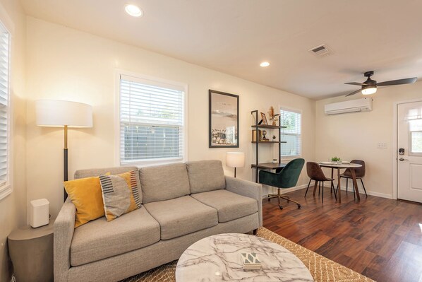 Living room features a comfortable couch, TV w/ Roku, dedicated workspace
