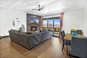 Inviting living room with a cozy sofa, outdoor access to the deck, and stunning views of the mountains.