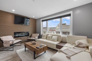 Living room with large comfy couch, smart TV, and electric fireplace perfect for a movie night or an afternoon nap! *This couch also doubles as an additional sleeping option.