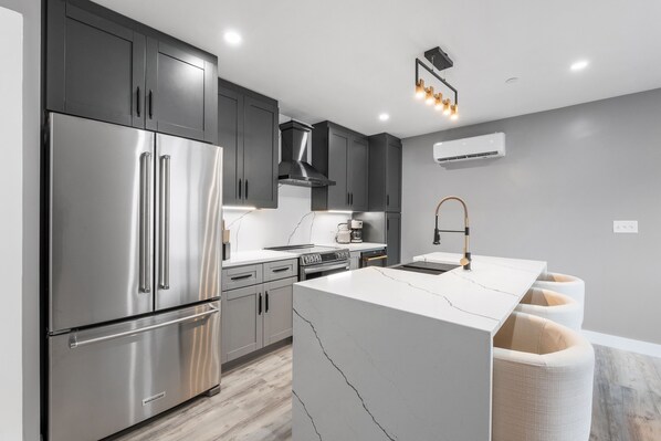 Brand new modern kitchen, featuring stainless steel appliances in a bright and open layout. 