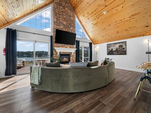 Relax in the inviting living room, featuring high ceilings, a stone fireplace, and breathtaking lake views!