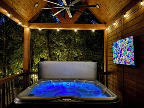Relaxing outdoor hot tub with ambient lighting and vibrant TV display.
