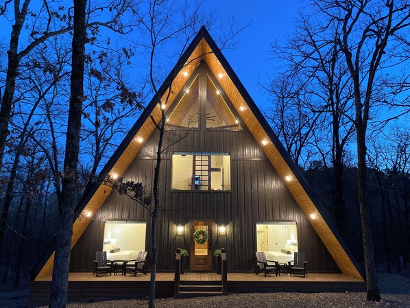 Warmly lit Yay frame cabin surrounded by tranquil forest at dusk