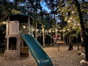 Magical forest playground with slide, hoop, and sparkling lights.