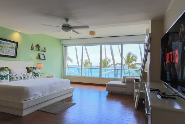 Main room with a king-size bed, breathtaking beach views, smart TV, walk-in closet, and a spacious bathroom.