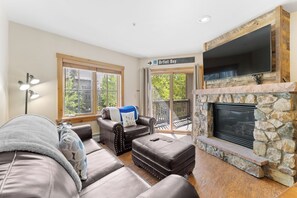 Living area with mounted flat screen TV, hardwood flooring, gas fireplace, sleeper sofa, and access to the private balcony.