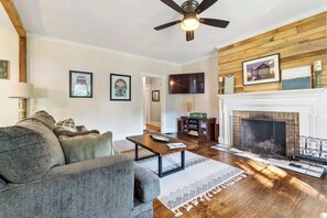 Relax in the inviting living area, complete with a couch, oversized TV, chic accent chairs, and a decorative fireplace that adds charm (non-operational). The open layout enhances the space, making it perfect for unwinding or gathering with friends.