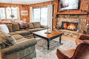 Relax by the wood burning fireplace in this cozy living room with large TV